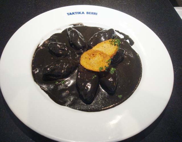 Un plato blanco con una salsa negra y un trozo de patata encima.