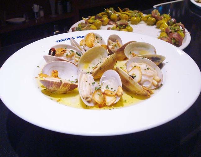 Un plato blanco cubierto con almejas y ajo se encuentra sobre una mesa.