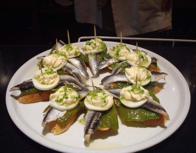 Un plato blanco cubierto con pescado y huevos en palillos.