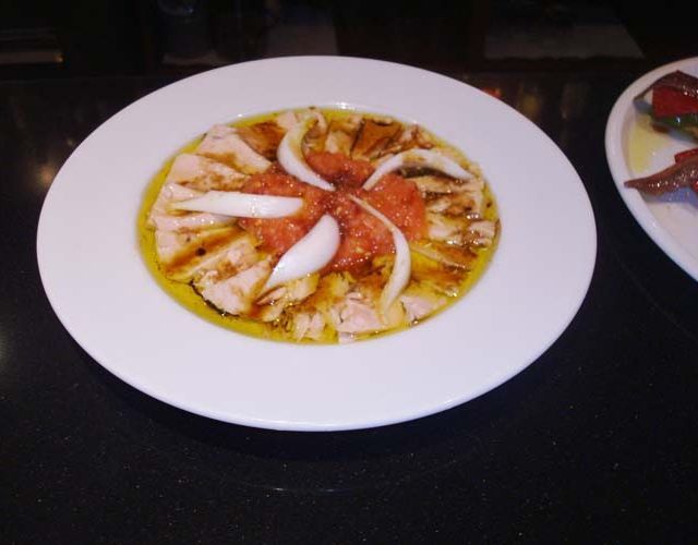 Un plato de comida con tomates y cebollas en una mesa.