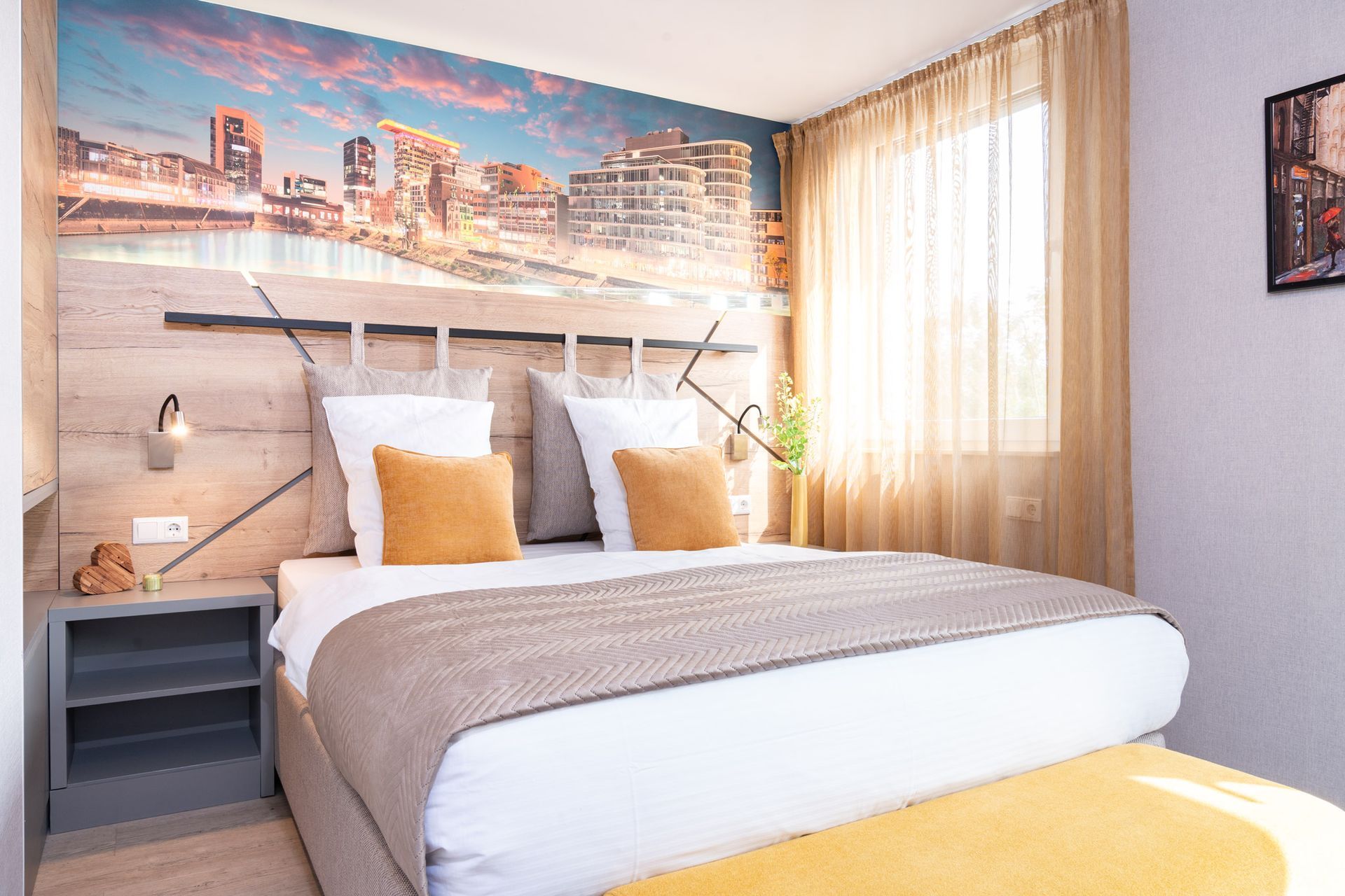 Schlafzimmer mit Stadtpanorama-Wandbild, Kingsize-Bett, Akzenten in Beige und Orange.