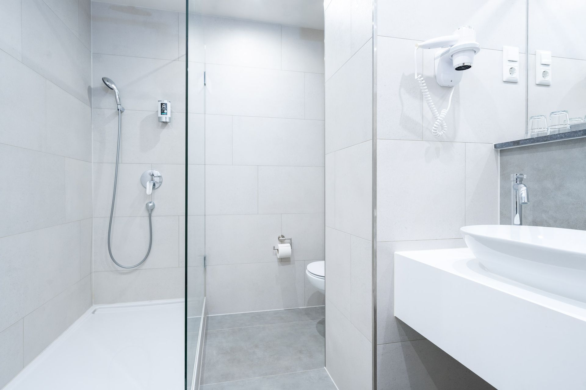 Modernes weißes Badezimmer mit Dusche, Toilette und Waschbecken.