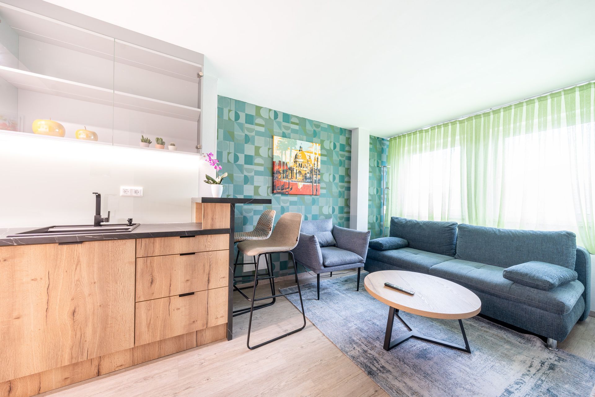 Modernes Wohnzimmer mit Kochnische, Sofa und kleinem Couchtisch.