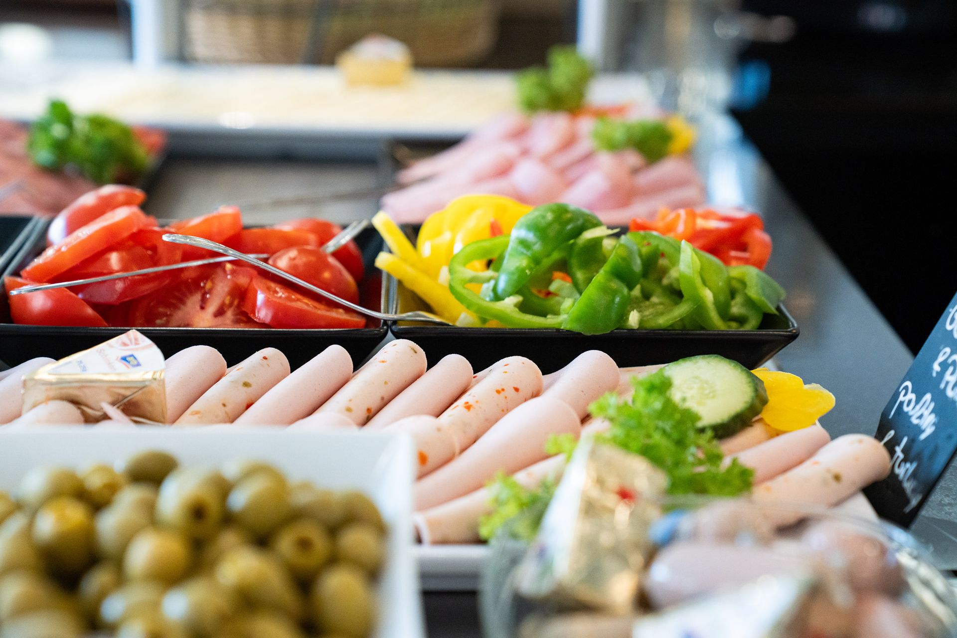 Buffet mit Aufschnitt, Tomaten, Paprika, Oliven und Würstchen.