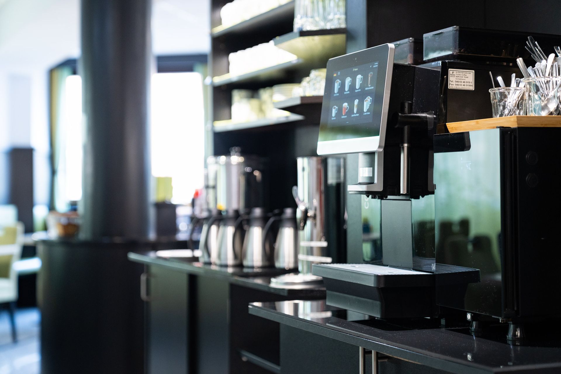 Kaffeestation mit automatisiertem Brühsystem, Edelstahlkaraffen und Gläsern.