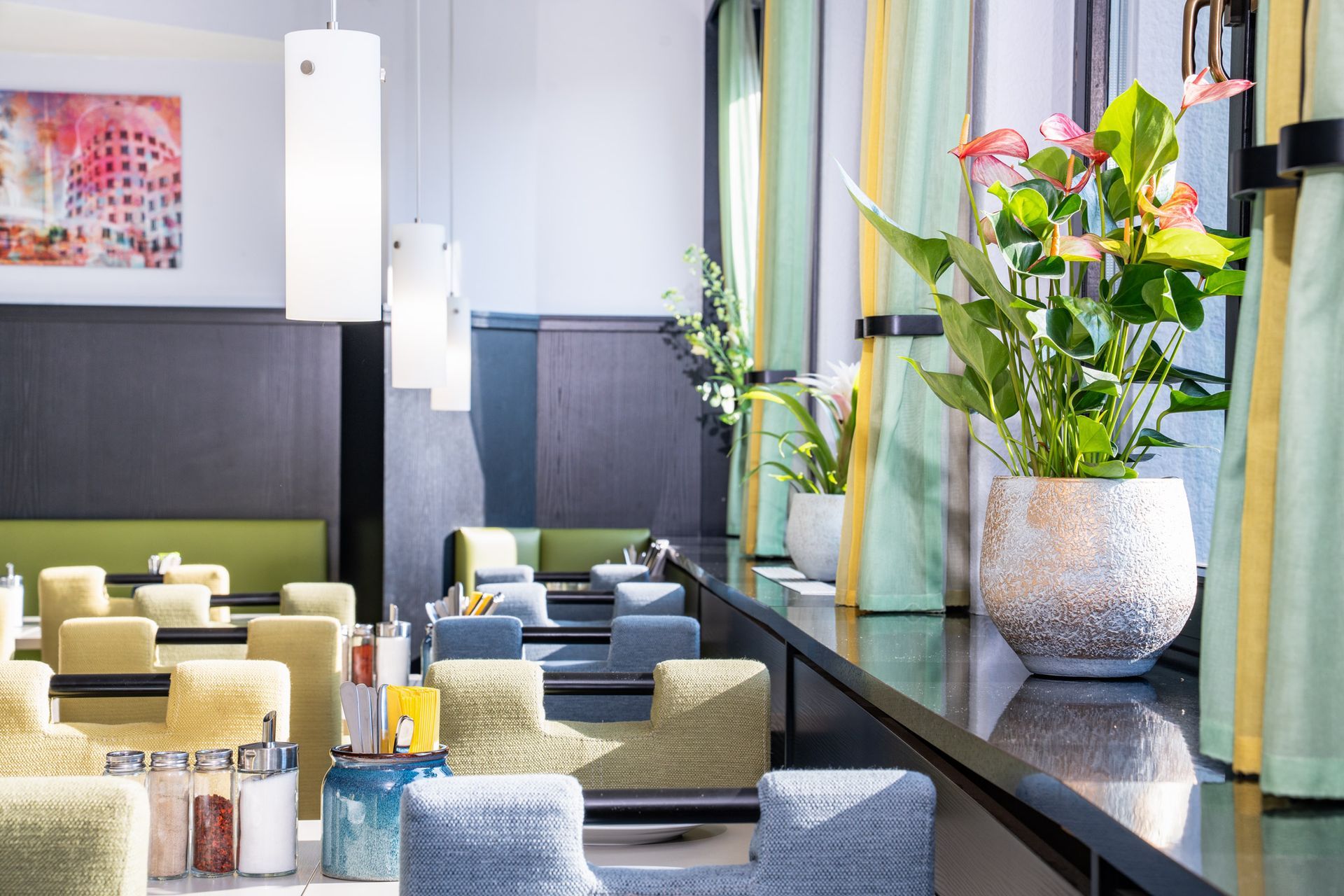 Restaurantinterieur mit Sitzgelegenheiten, Pflanzen und Sonnenlicht.