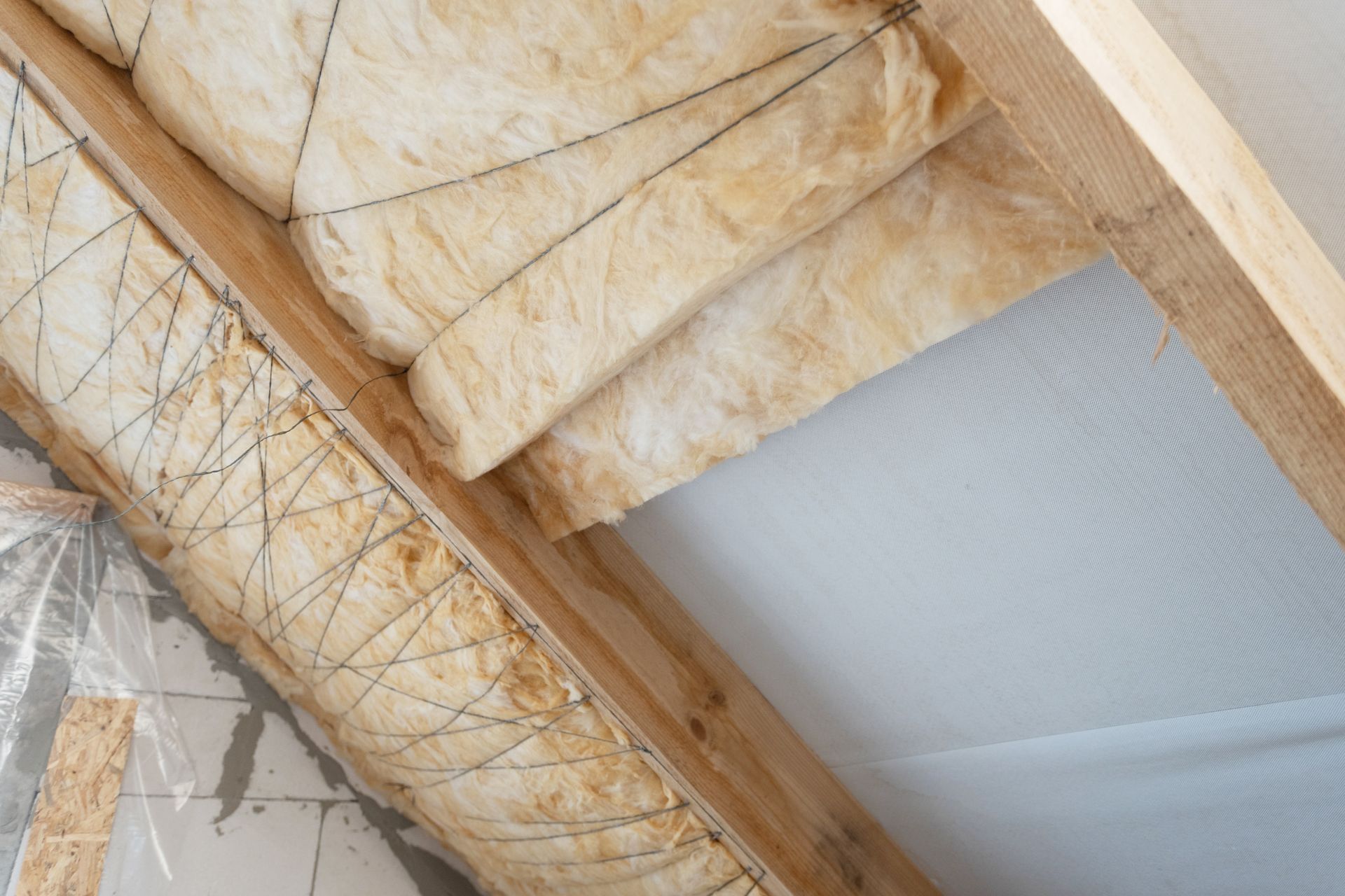 De l'isolant en fibre de verre est placé entre les solives de plafond en bois, laissant apparaître une section de pare-vapeur.