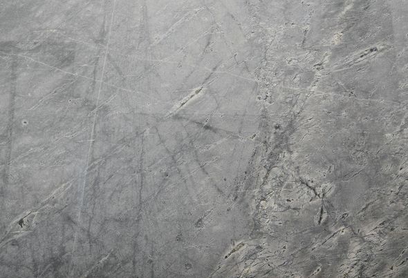 Harmaa kuvioitu betonipinta, jossa on hienovaraisia ​​naarmuja ja kirjavia kuvioita