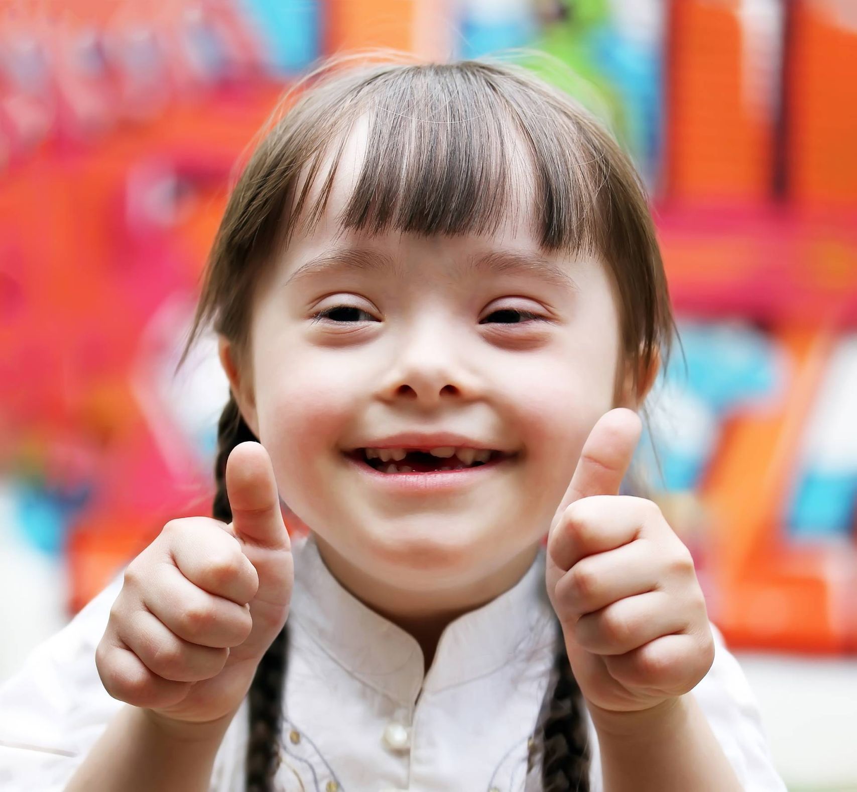 Kleines Mädchen mit Down-Syndrom freut sich über eine erfolgreiche logopädischen Behandlung