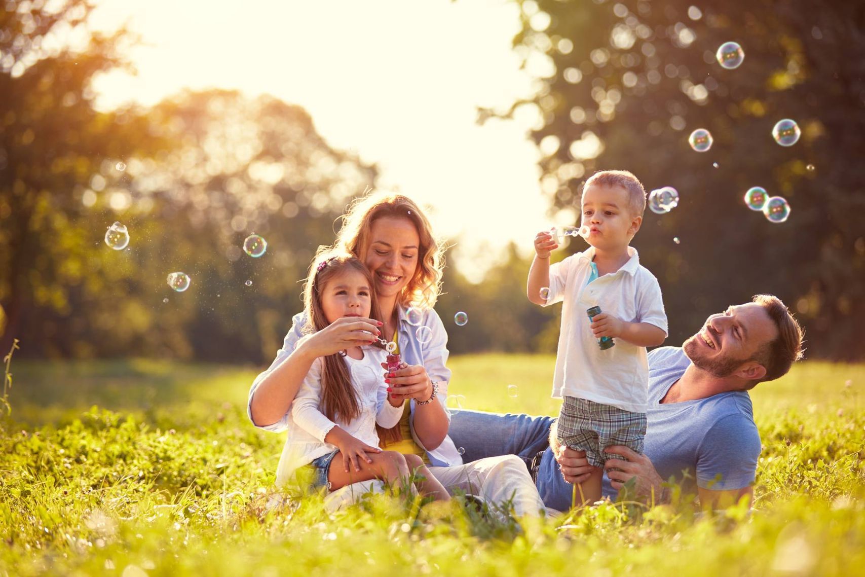 Nach einer erfolgreichen Logopädiestunde sitzt eine Familie in der Natur.