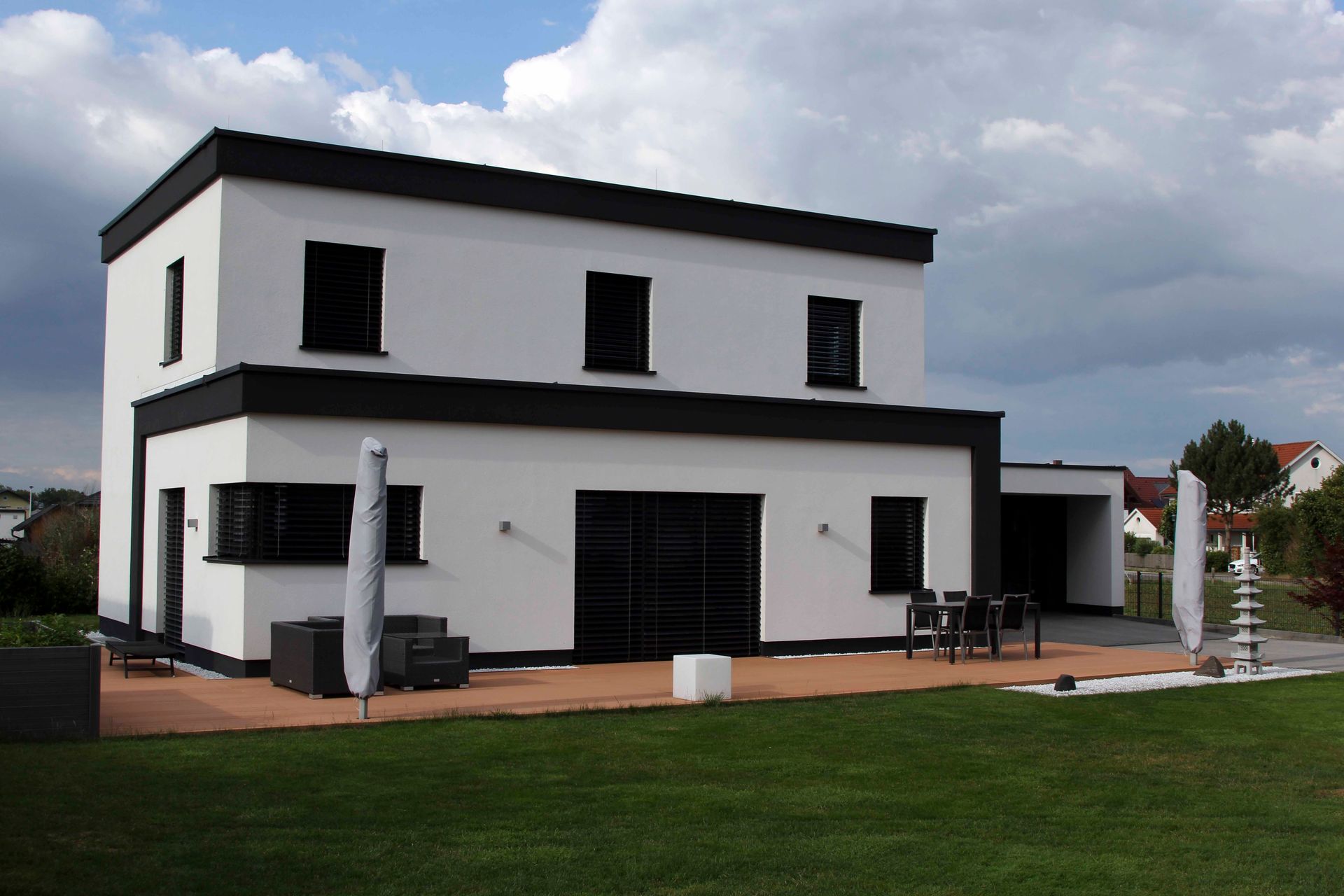 Ein weiß-schwarzes Haus mit einer Terrasse davor