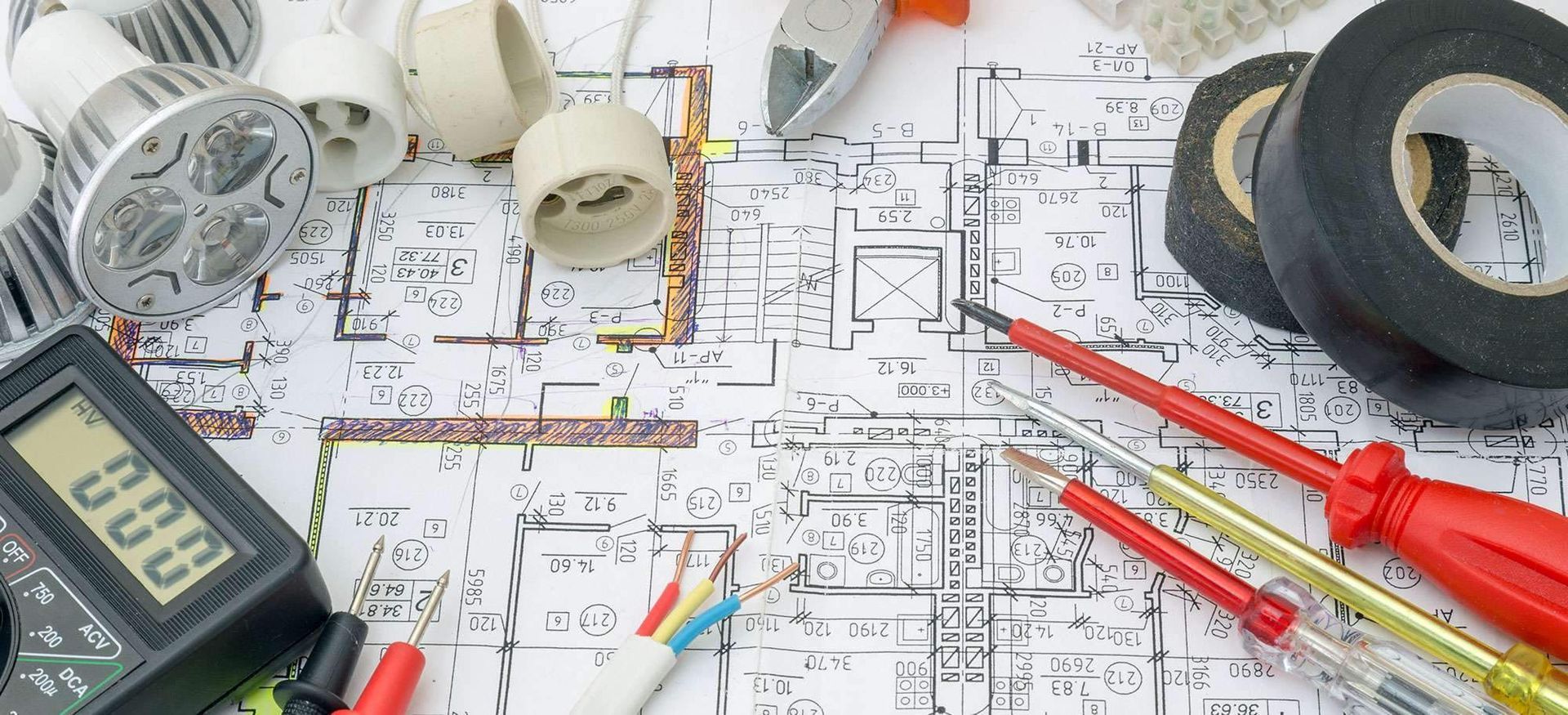 Architekturpläne, Taschenrechner, rote Stifte, Lineal und Klebebandrollen auf einer Arbeitsfläche