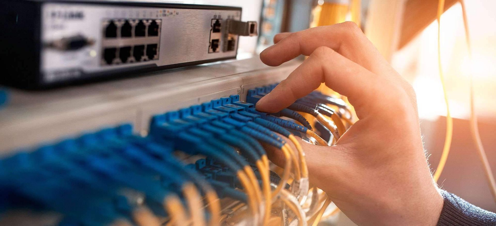 Manuelles Verbinden blauer Ethernet-Kabel mit einem Netzwerk-Switch in einem Serverraum