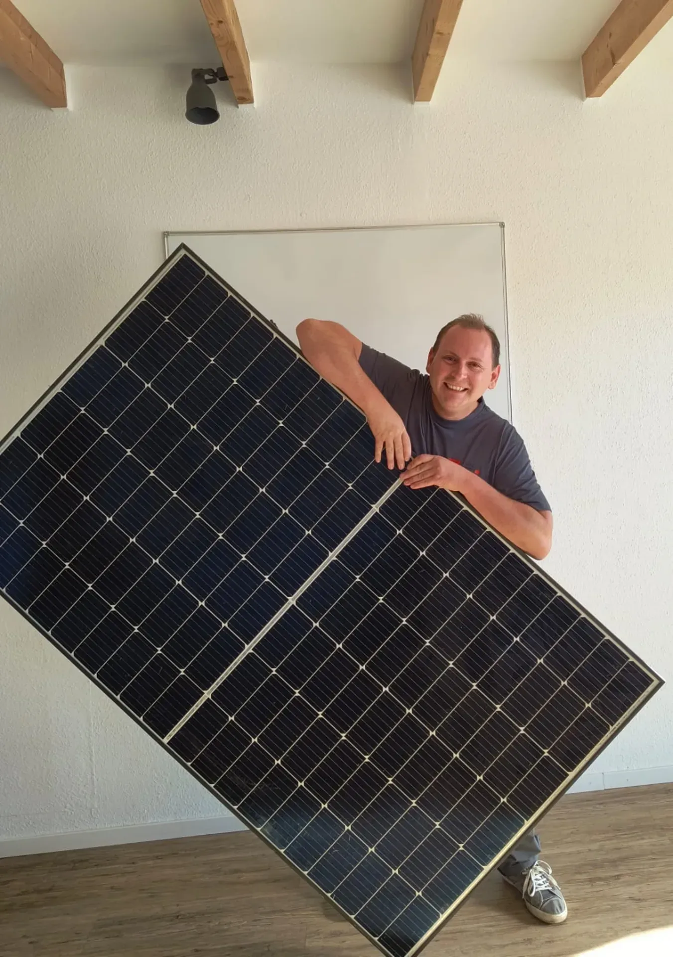 Person lehnt sich in einem Innenraum hinter einem großen Solarpanel