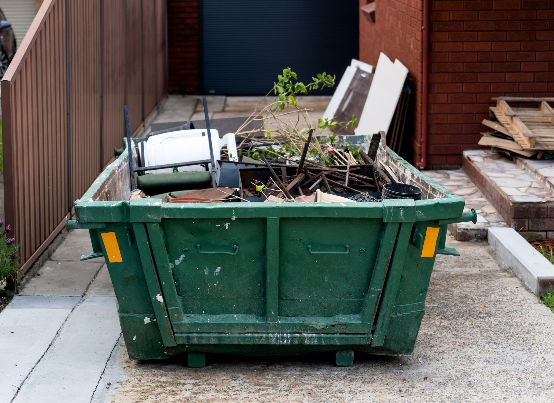 Benne tout-venant contenant de la ferraille et une chaise en plastique.
