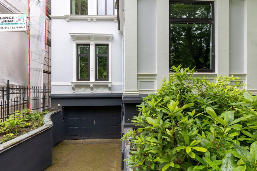 Ein weißes Haus mit einem schwarzen Garagentor und einem schwarzen Fenster.