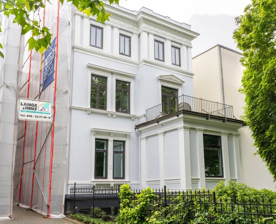 Ein großes weißes Gebäude mit einem Gerüst darum wird gestrichen.