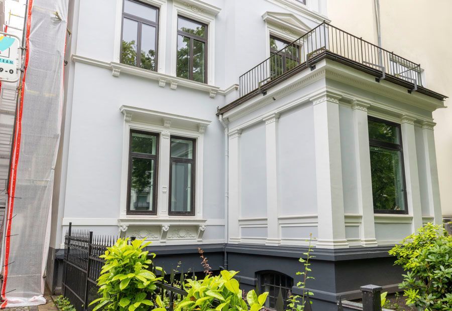 Ein großes weißes Haus mit Balkon wird gestrichen.