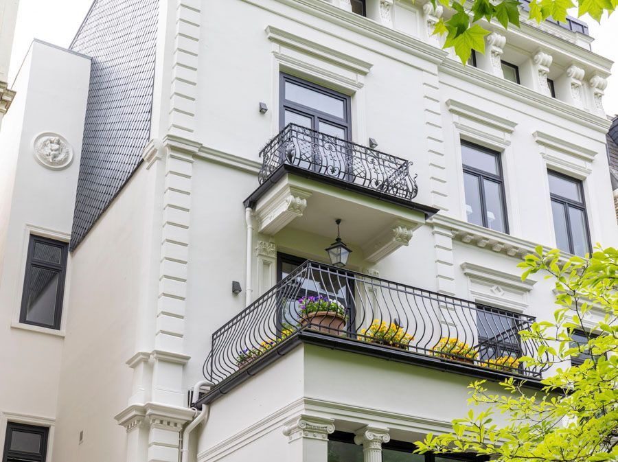 Ein weißes Gebäude mit einem Balkon und Blumen darauf