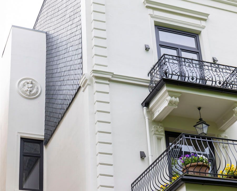 Ein weißes Gebäude mit einem Balkon und Blumen darauf.