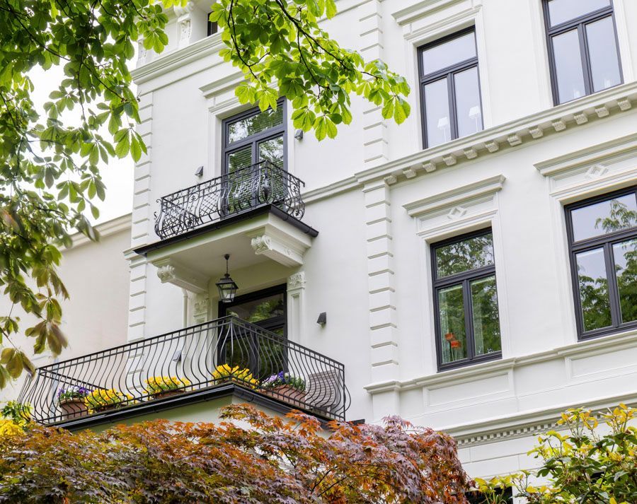 Ein großes weißes Gebäude mit einem Balkon und schwarzen Fenstern.