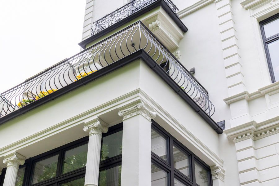 Ein weißes Gebäude mit schwarzen Fenstern und einem Balkon.