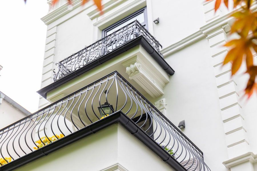 Ein Balkon an der Seite eines Gebäudes mit einem schmiedeeisernen Geländer