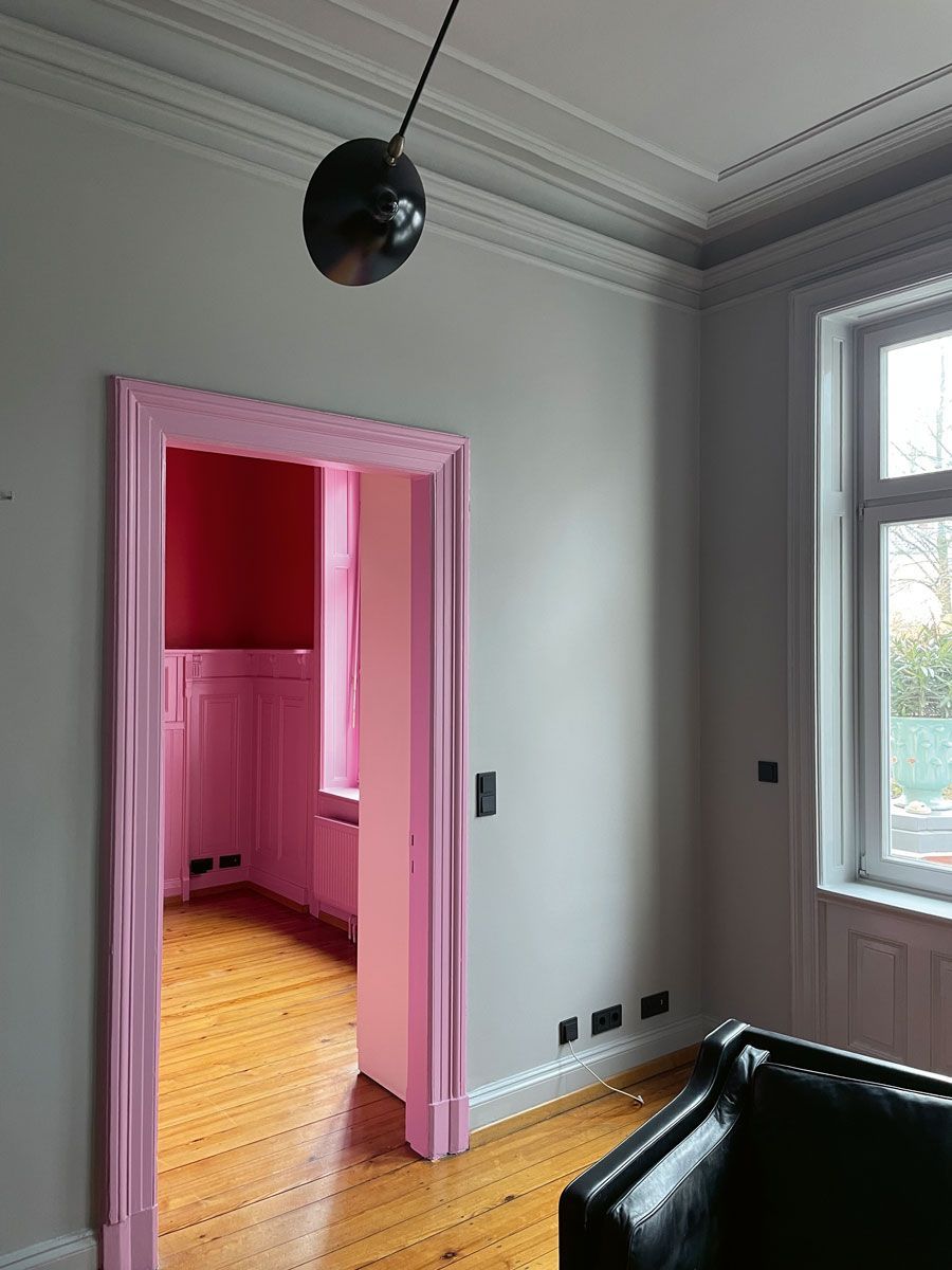 Ein Wohnzimmer mit einer rosa Tür und einem schwarzen Stuhl.