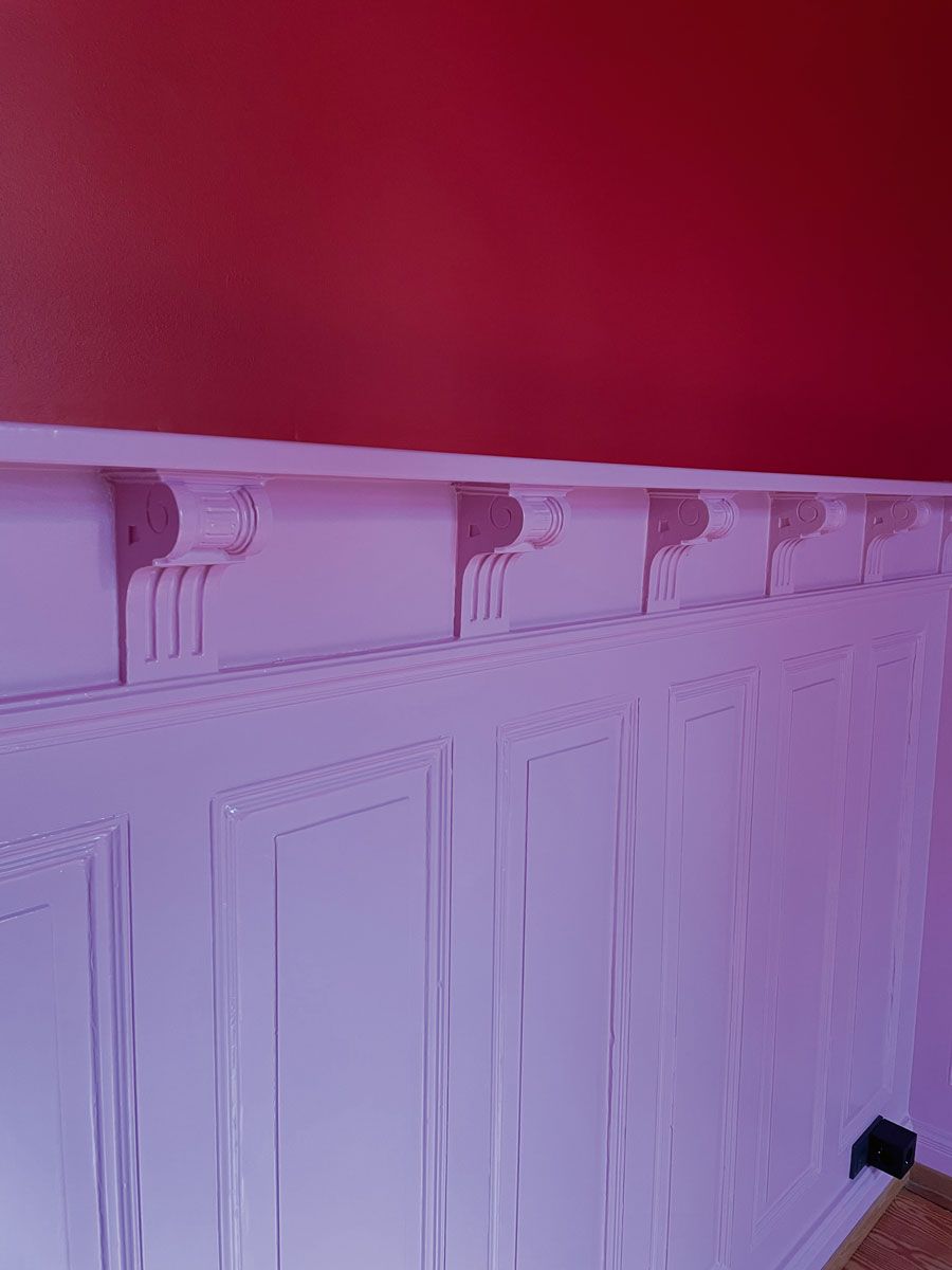 Eine weiße Wand mit einer roten Wand dahinter.