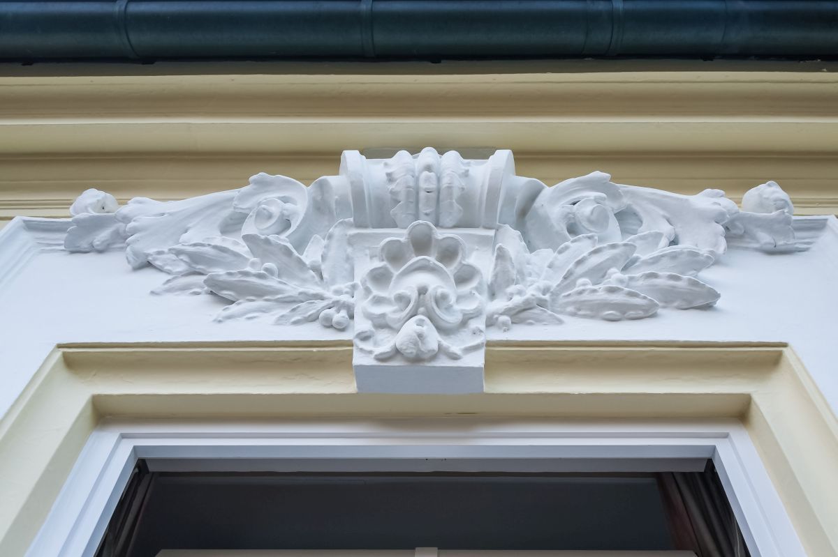 Ein weiß-gelbes Gebäude mit einer aufwendigen Verzierung über einem Fenster.