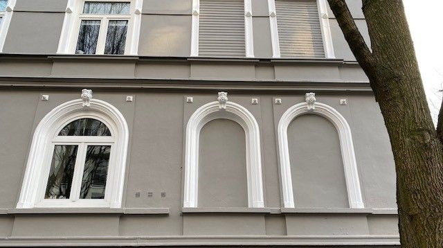 Ein Gebäude mit Bogenfenstern und einem Baum davor.