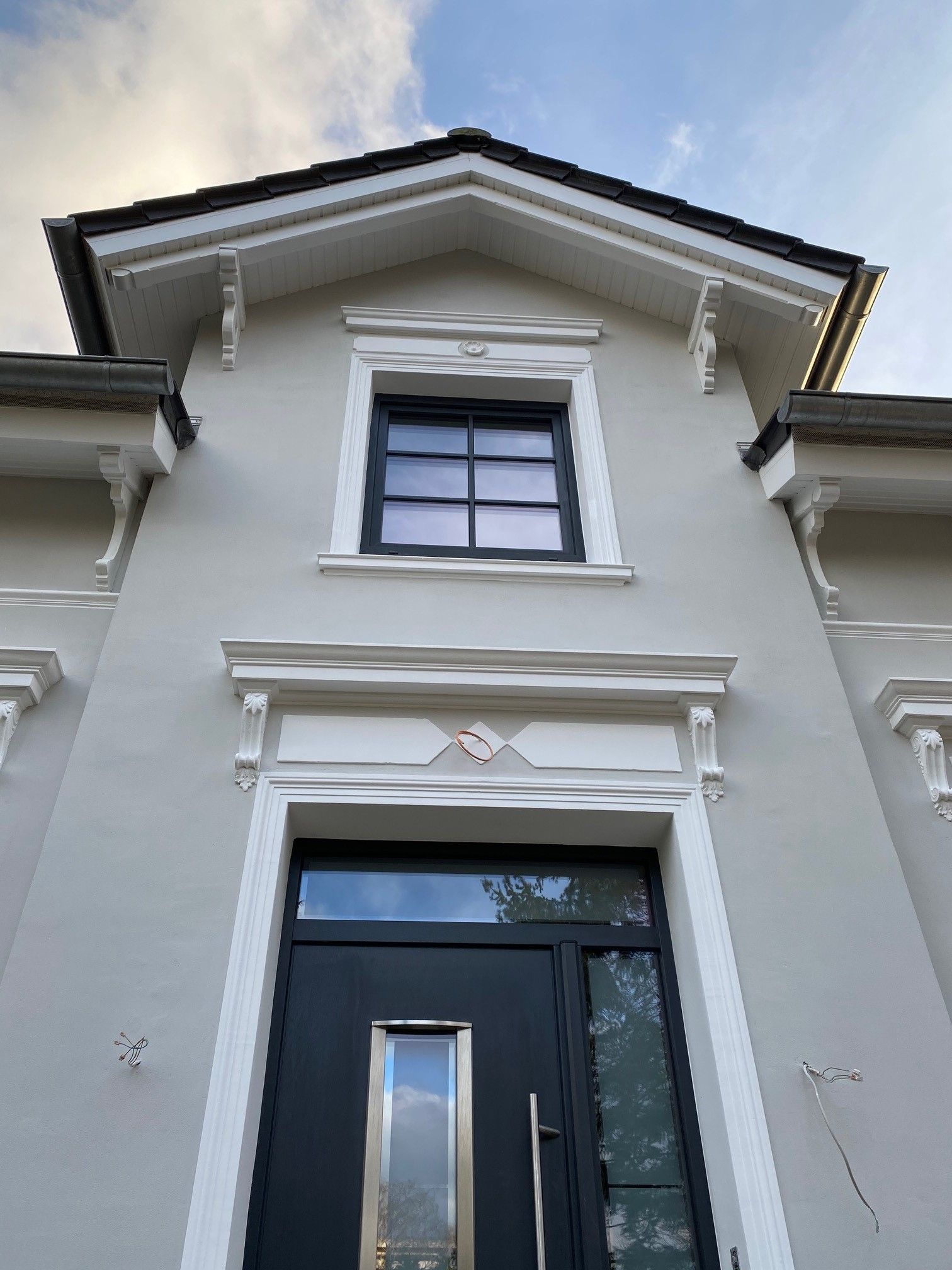 Die Vorderseite eines Hauses mit einer schwarzen Tür und einem Fenster.