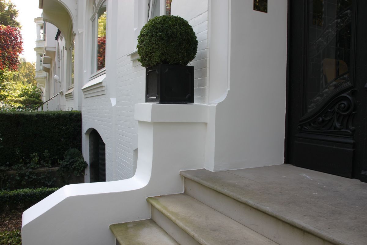 Ein weißes Haus mit einer schwarzen Tür und Treppe