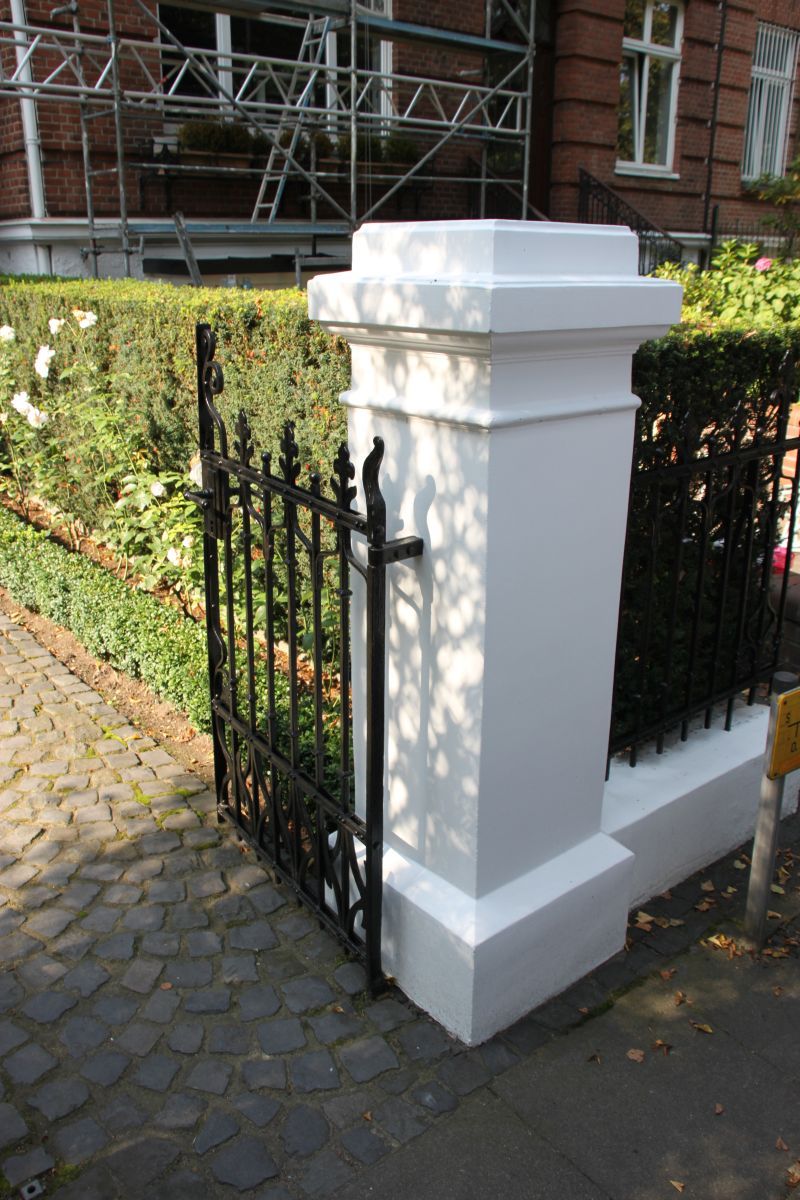Eine weiße Säule mit einem schwarzen Tor vor einem Gebäude