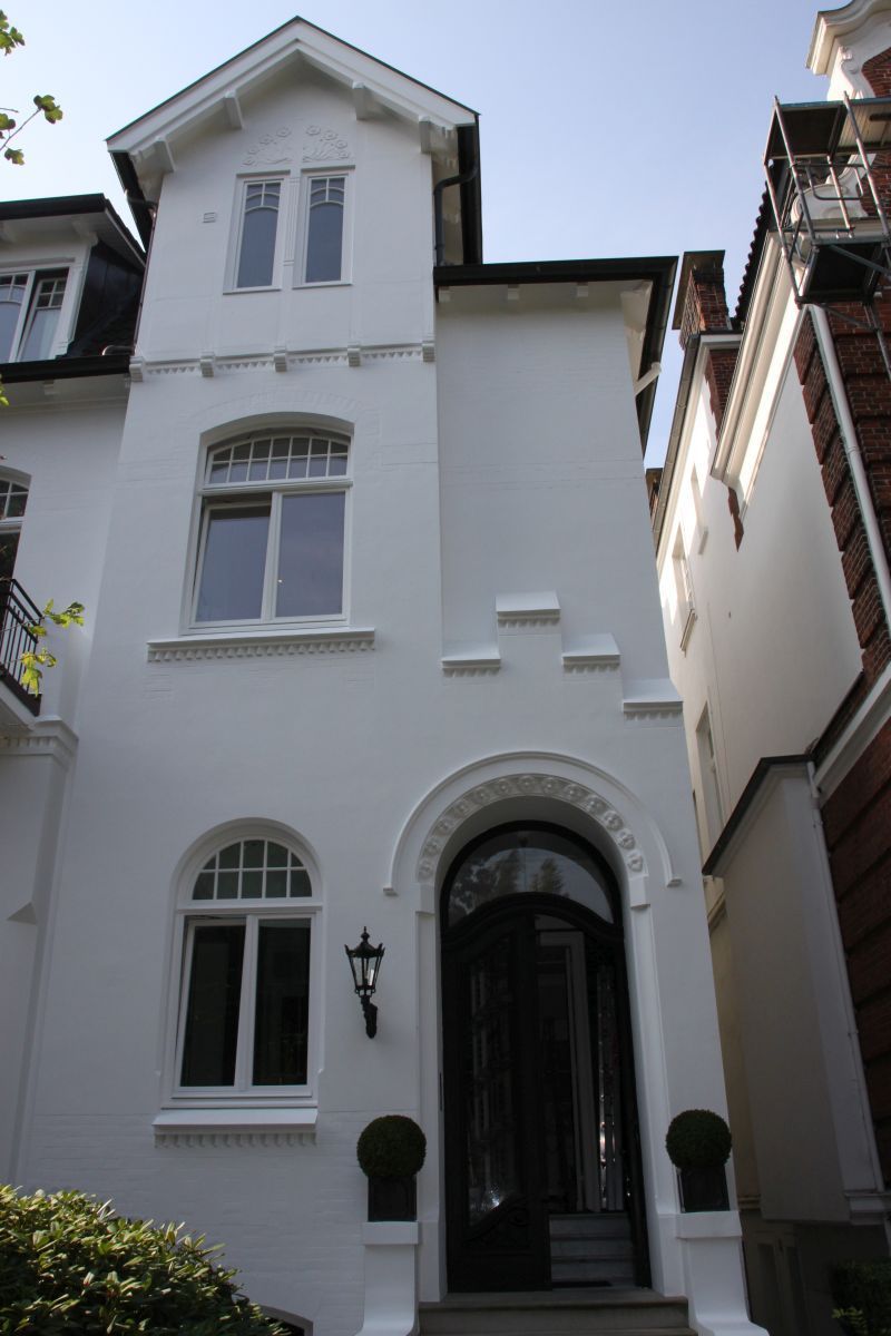 Ein weißes Gebäude mit einer schwarzen Tür und schwarzen Fenstern