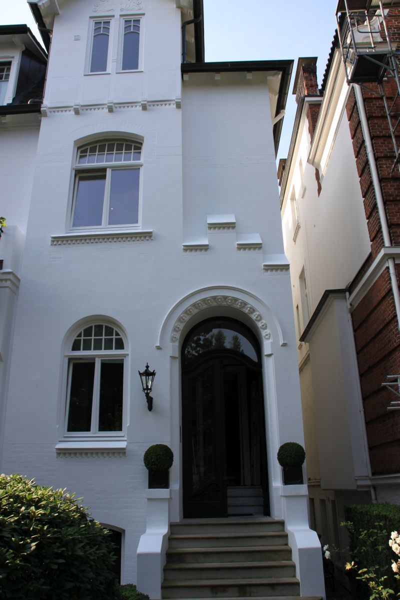 Ein weißes Gebäude mit einer schwarzen Tür und Treppe