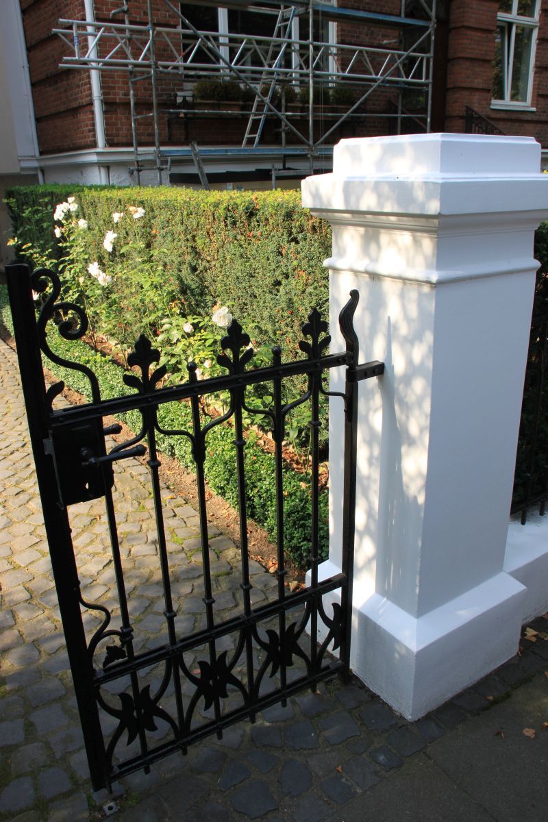 Ein schwarzes Tor mit einer weißen Säule vor einem Gebäude