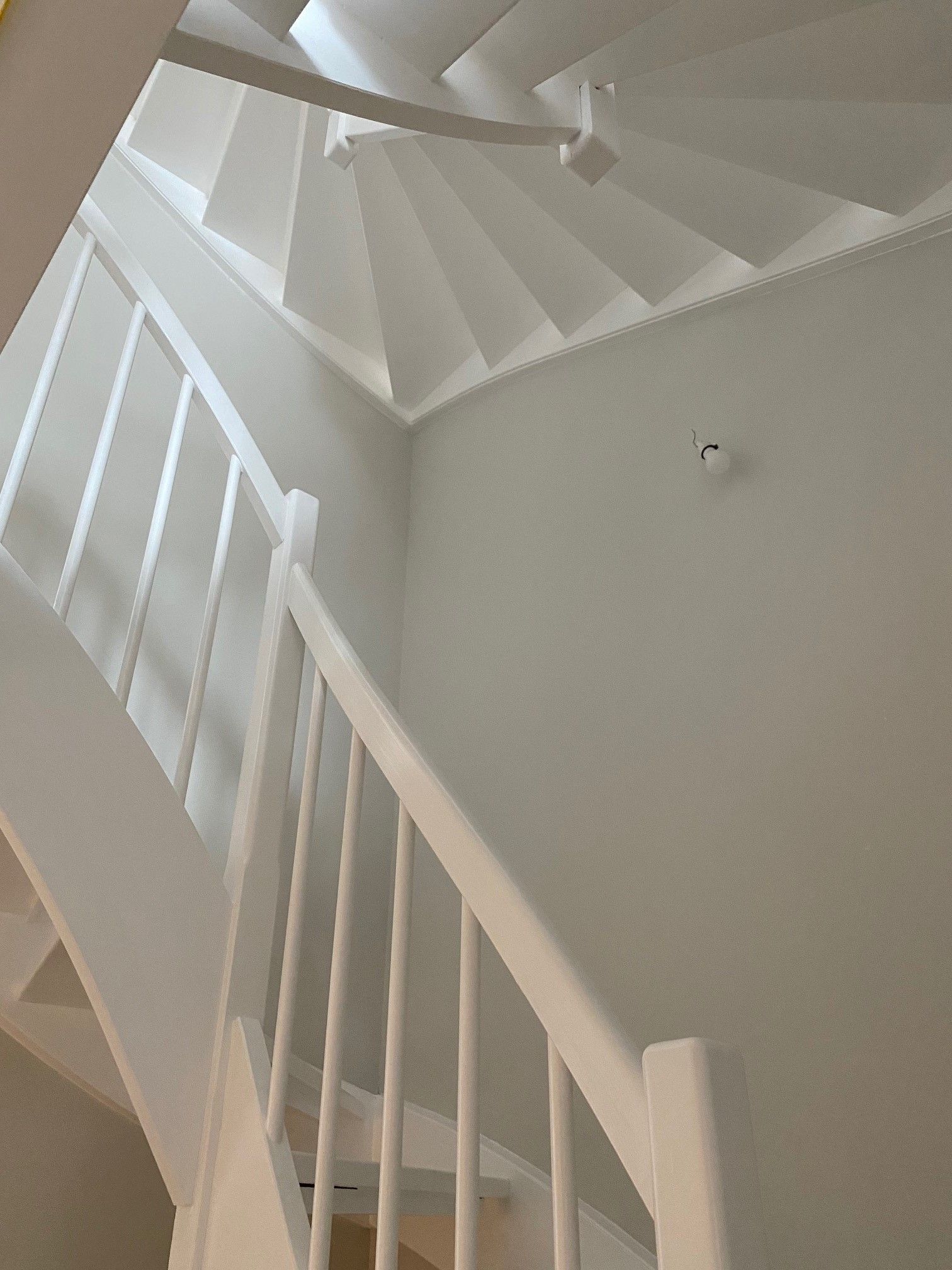 Blick nach oben auf eine weiße Wendeltreppe mit weißem Geländer