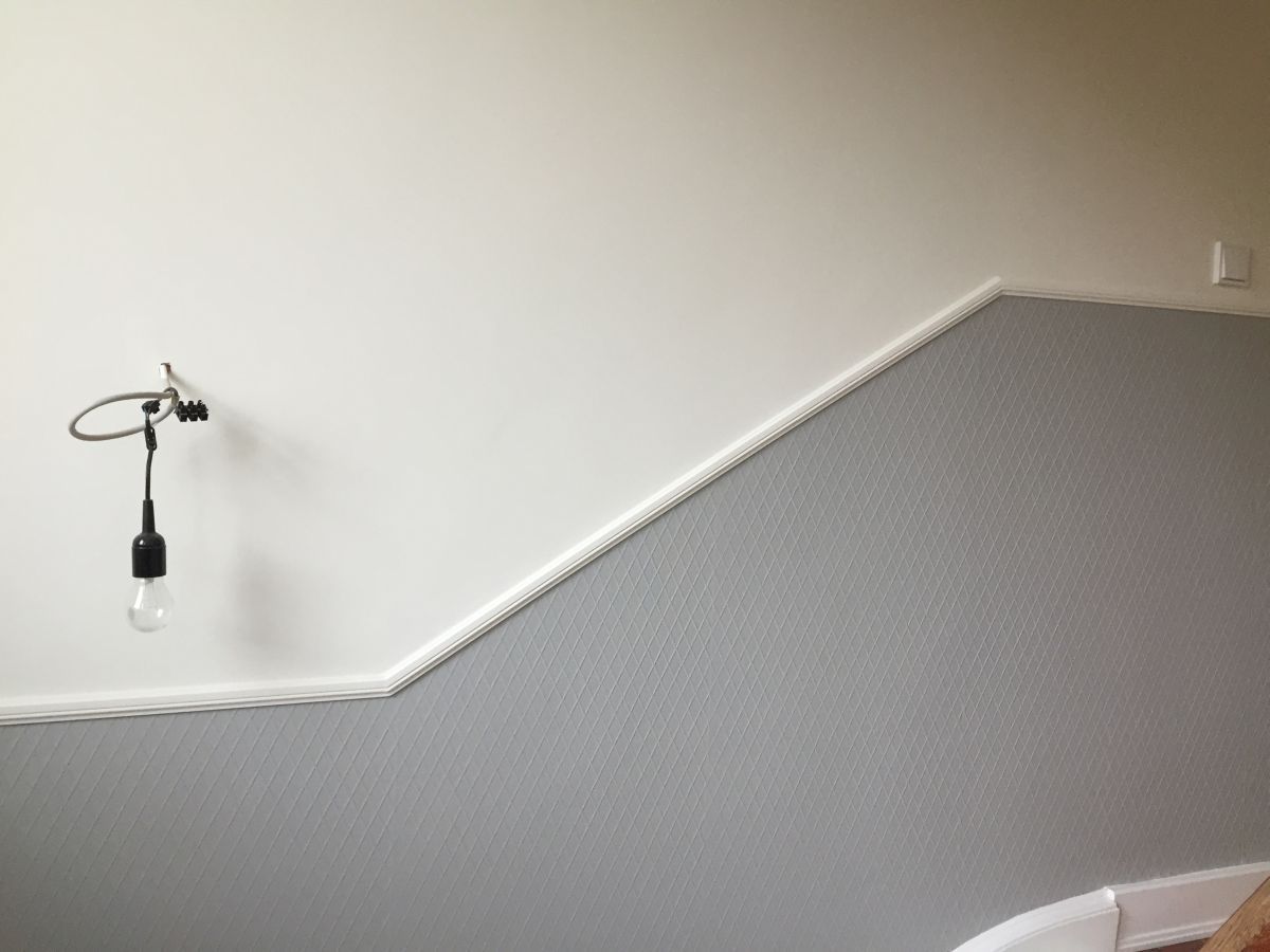 Eine Lampe hängt an einer Wand neben einem Bett