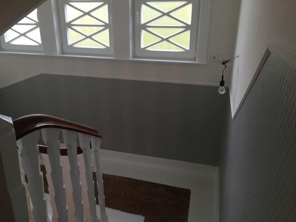 Eine Treppe mit weißem Geländer und drei Fenstern