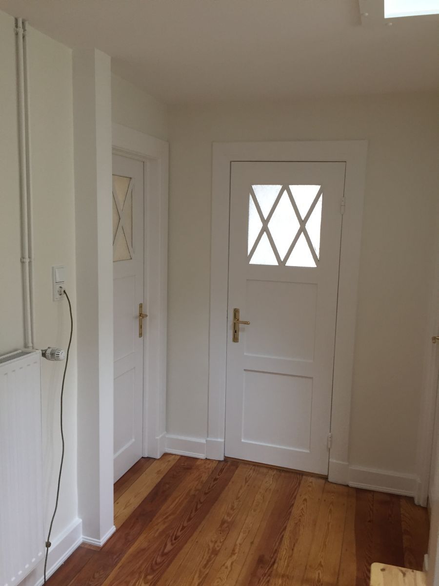 Ein Flur mit Holzboden und einer weißen Tür