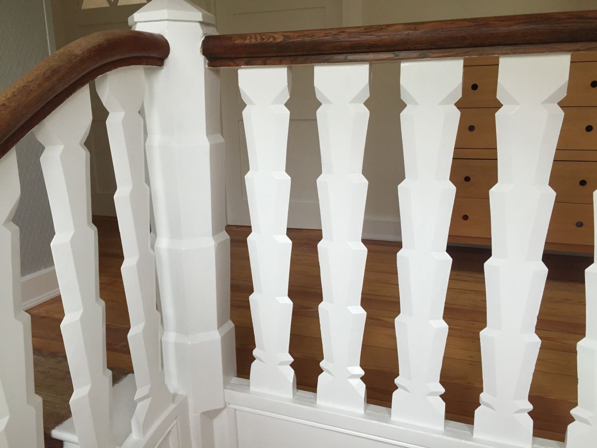 Ein weißes Geländer mit einem Holzhandlauf auf einer Treppe