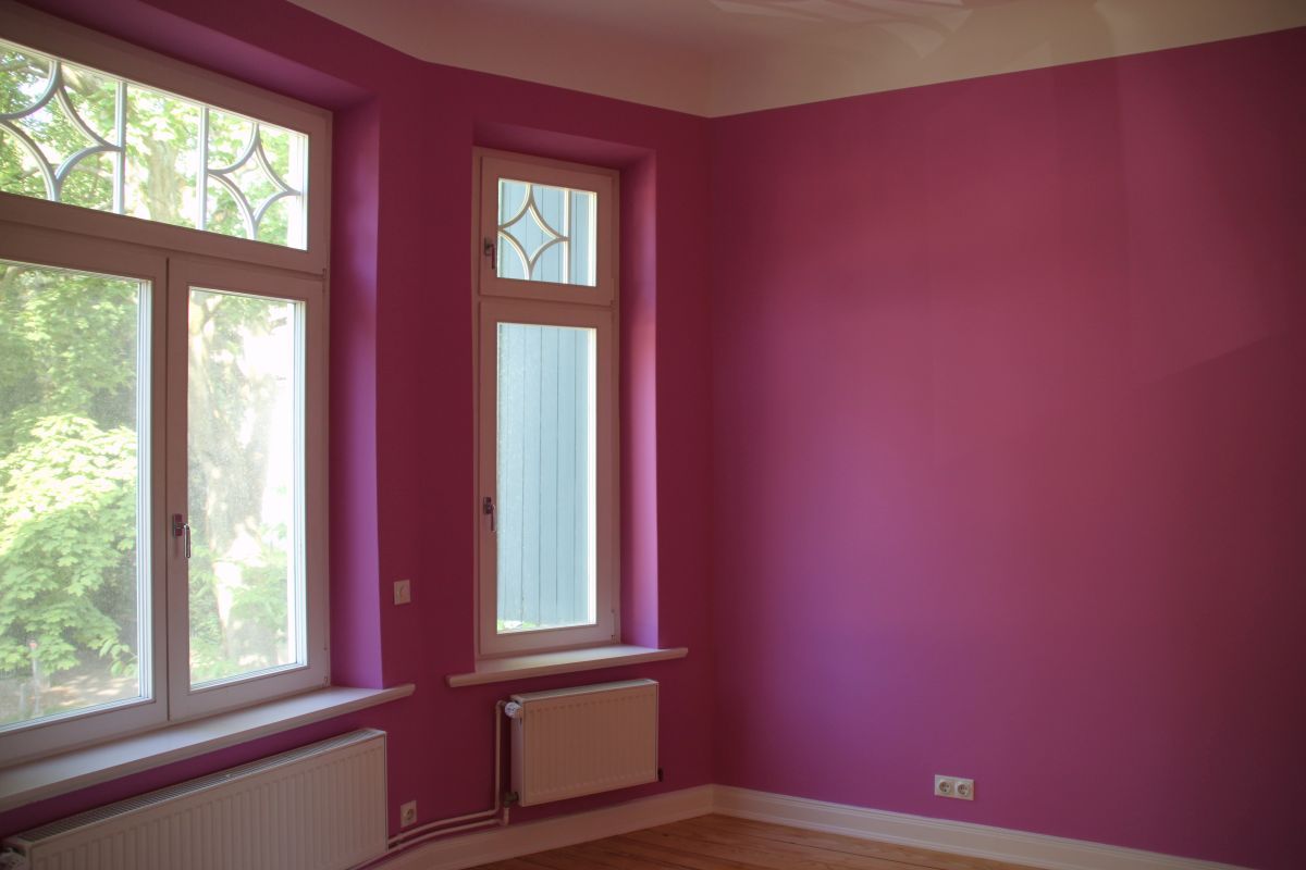 Ein leerer Raum mit rosa Wänden und einem Fenster.