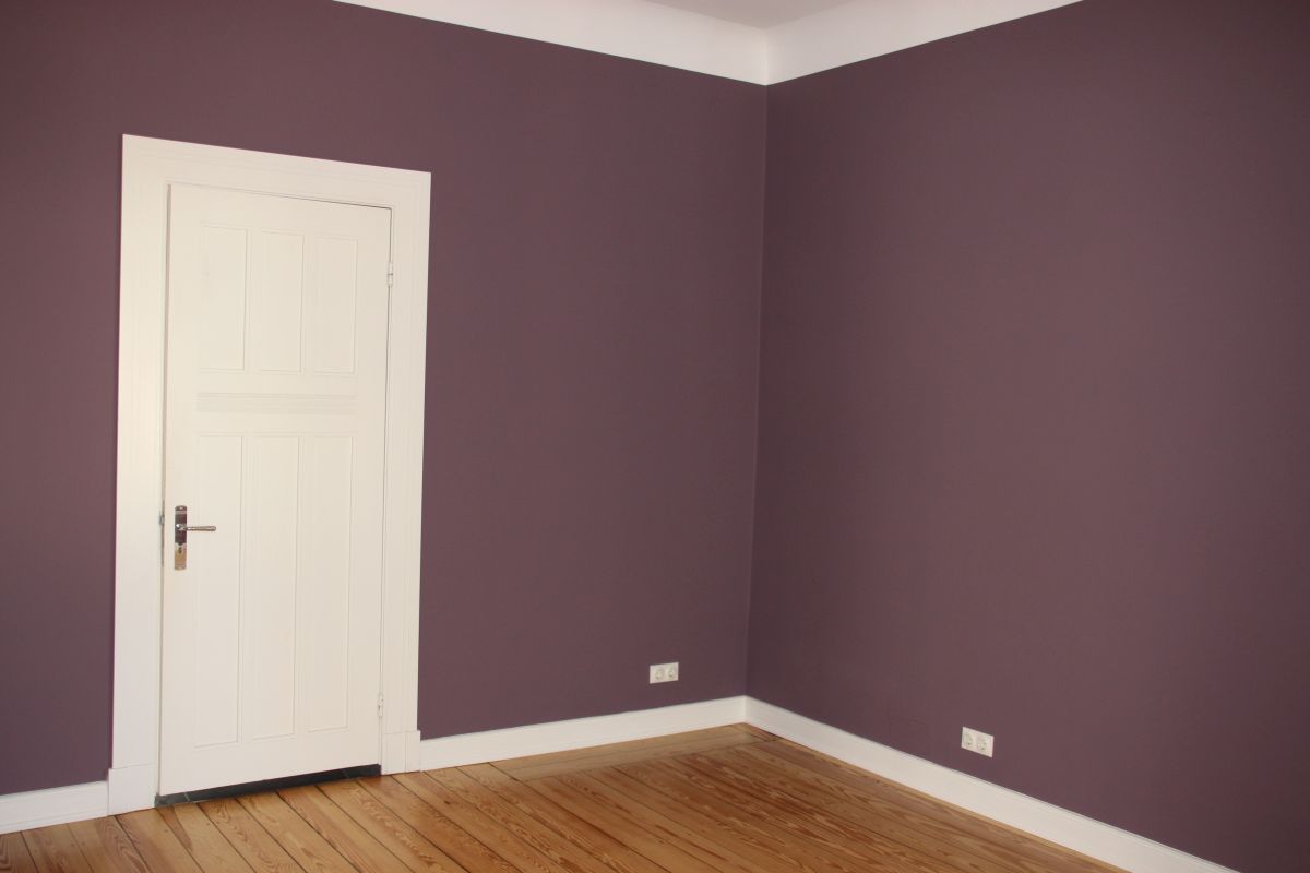 Ein leerer Raum mit violetten Wänden und einer weißen Tür