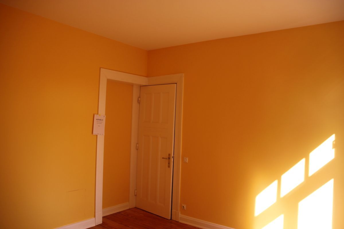 Ein leerer Raum mit gelben Wänden und einer weißen Tür