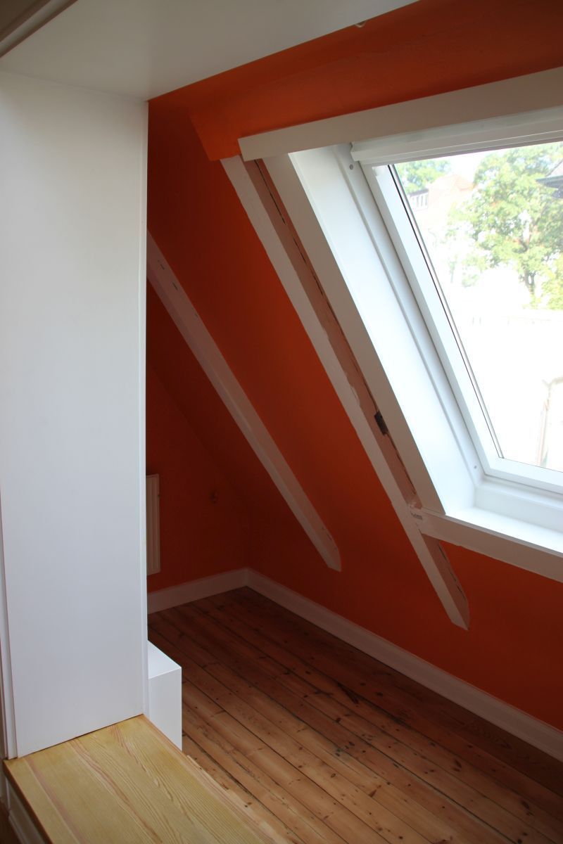 Ein leerer Raum mit orangefarbenen Wänden und einem Fenster