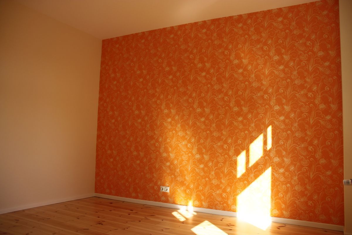 Ein leerer Raum mit orangefarbenen Wänden und einem Holzboden.