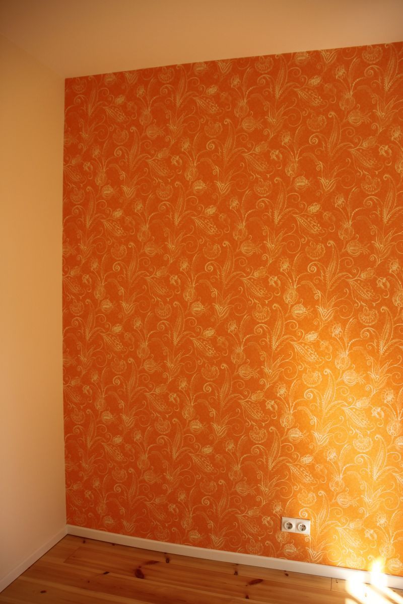 Ein Raum mit einer orangefarbenen Wand und einem Holzboden.