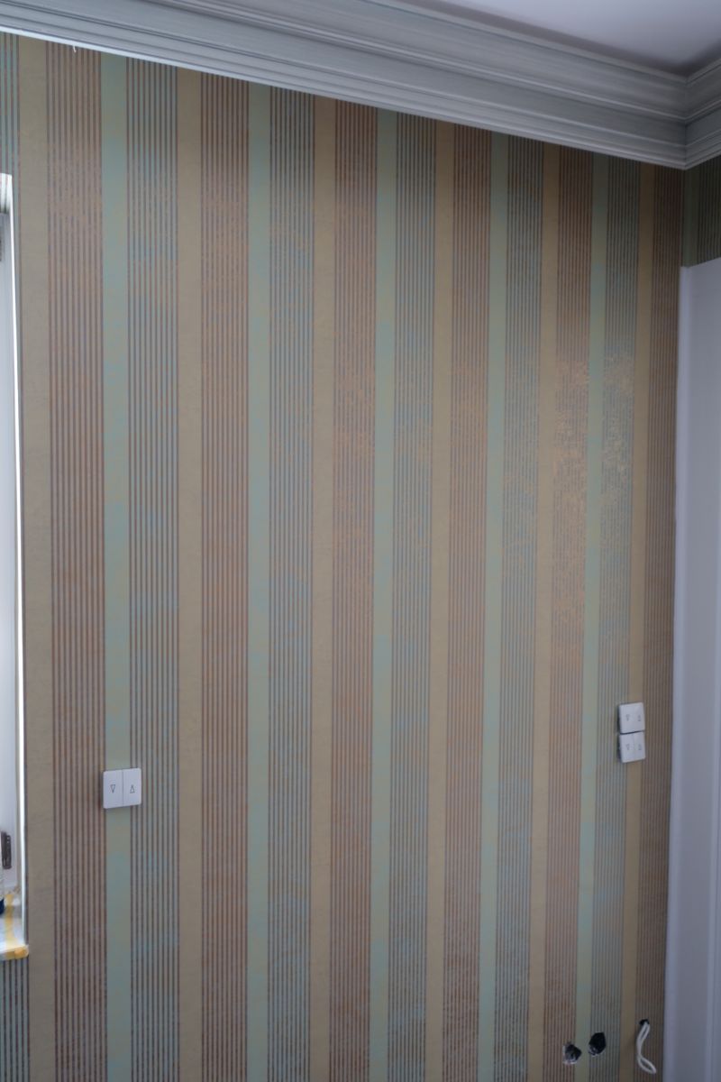 Ein Zimmer mit einer gestreiften Tapete an der Wand und einem Fenster.