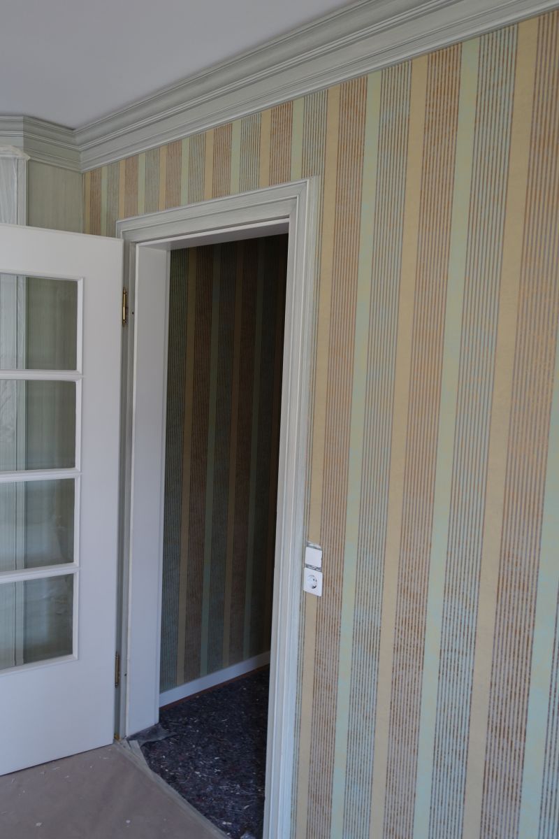 Ein Zimmer mit gestreifter Tapete und einer weißen Tür